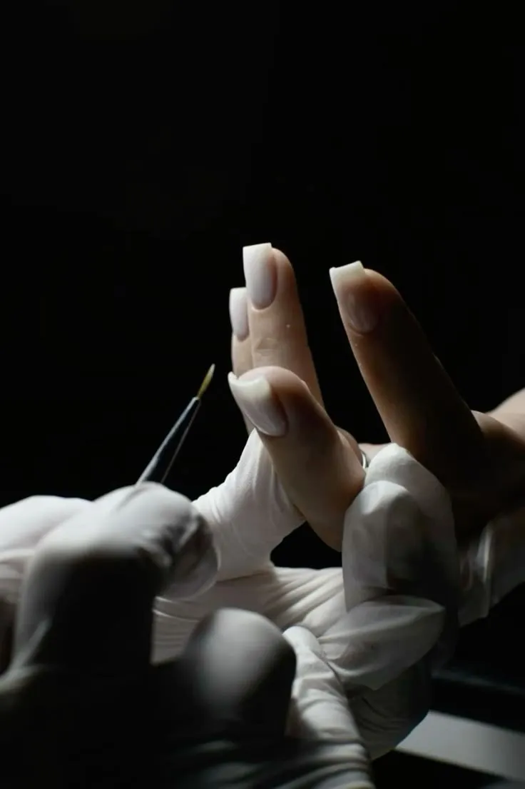 A nail artist refining a sculpted almond nail